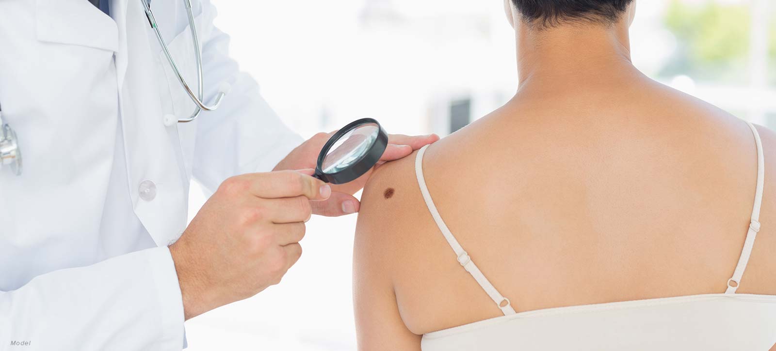 doctor looking at a mole on a patient's back